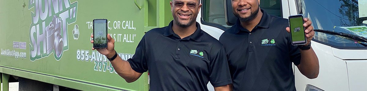 franchise owners holding app on phone in front of junk shot truck