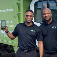 franchise owners holding app on phone in front of junk shot truck